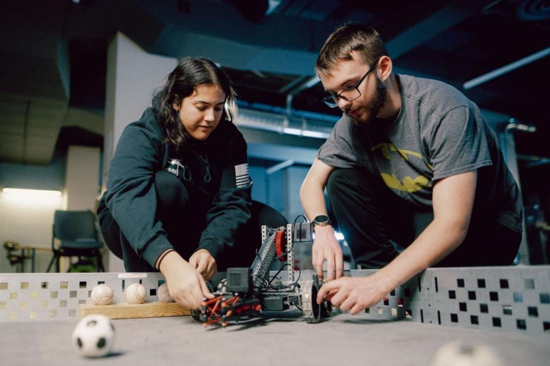 Two Kettering engineering students prepare to test a robot in a course filled with miniature balls